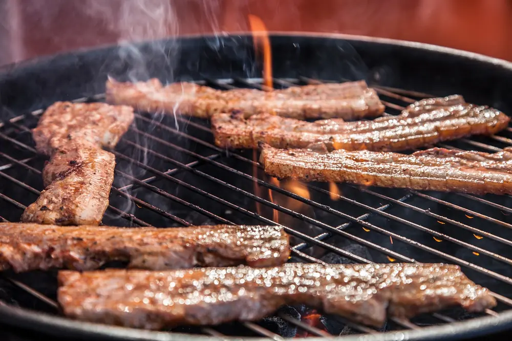 Meat cooking over open flames, reflecting the fire-driven kitchen at Ynyshir in Wales